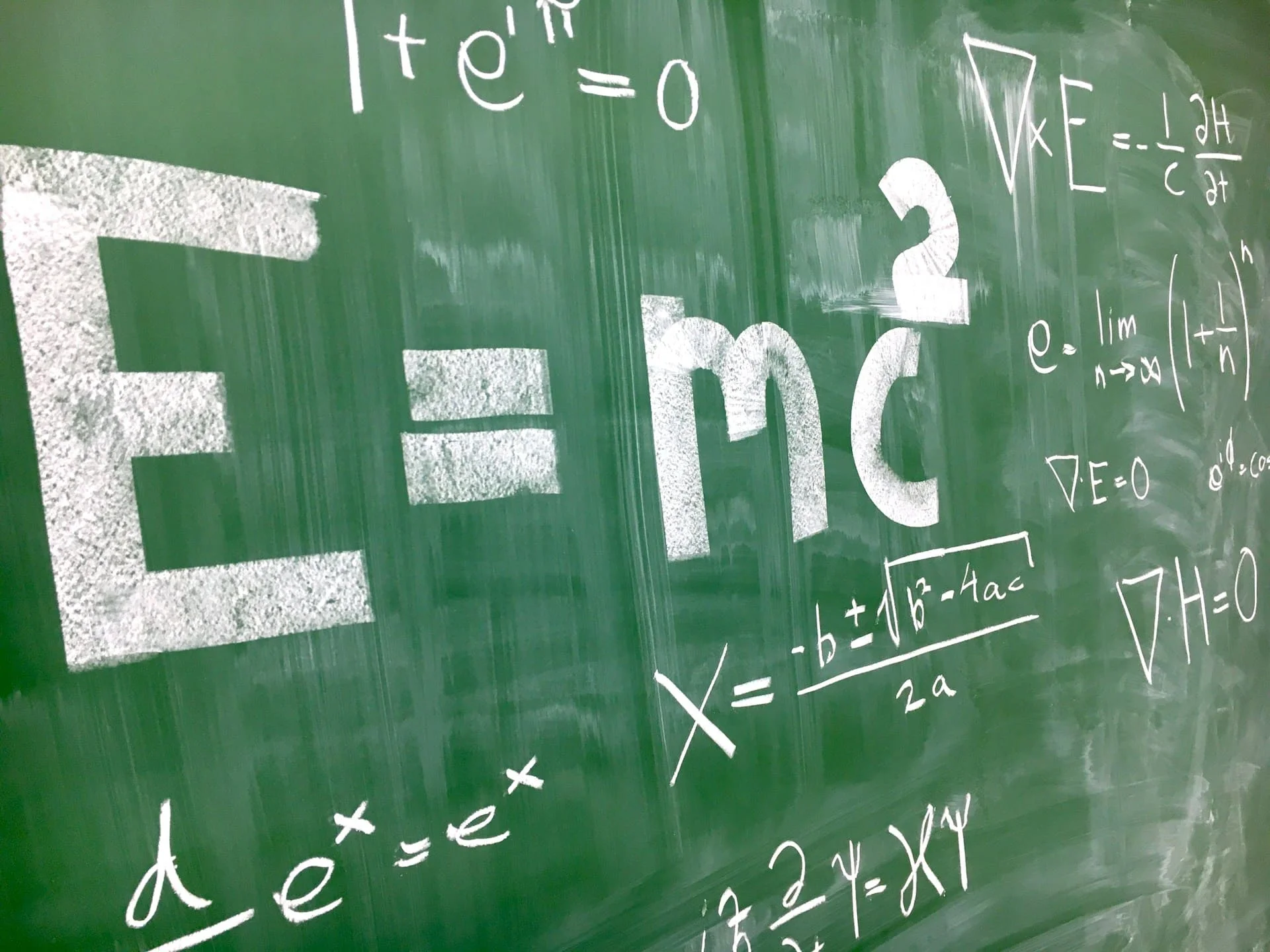 physics equations written on green chalkboard
