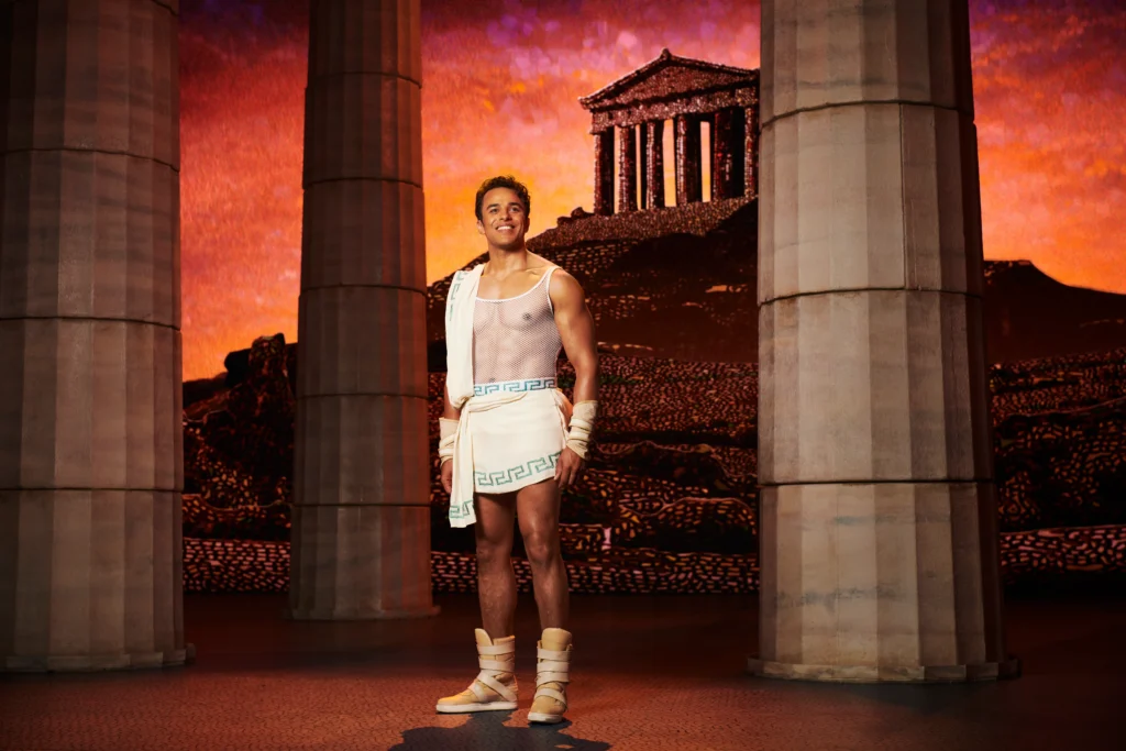Luke Brady as Hercules in Hercules at Theatre Royal Drury Lane, set against the stylised Mount Olympus backdrop. © Disney Theatrical Productions Photo by Matt Crockett