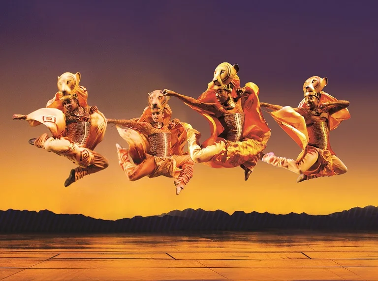 The Lion King cast leap mid air in one of the production’s most striking ensemble moments at the Lyceum Theatre, London. Photo Johan Persson