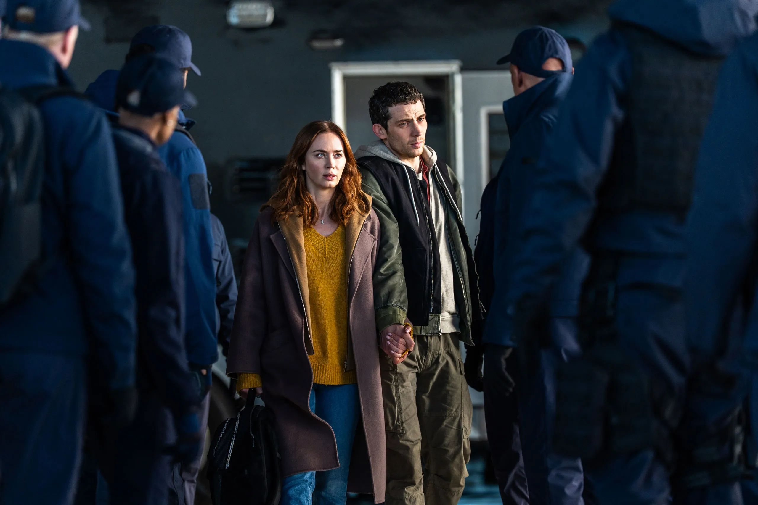 Emily Blunt and Josh O'Connor as Margaret and Daniel, surrounded by security personnel in Disclosure Day