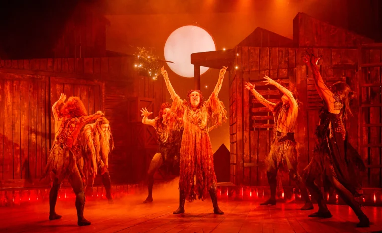 Our Dark of the Moon review captures the coven of witches raising their arms in a fiery, red lit ritual beneath the full moon at Charing Cross Theatre.