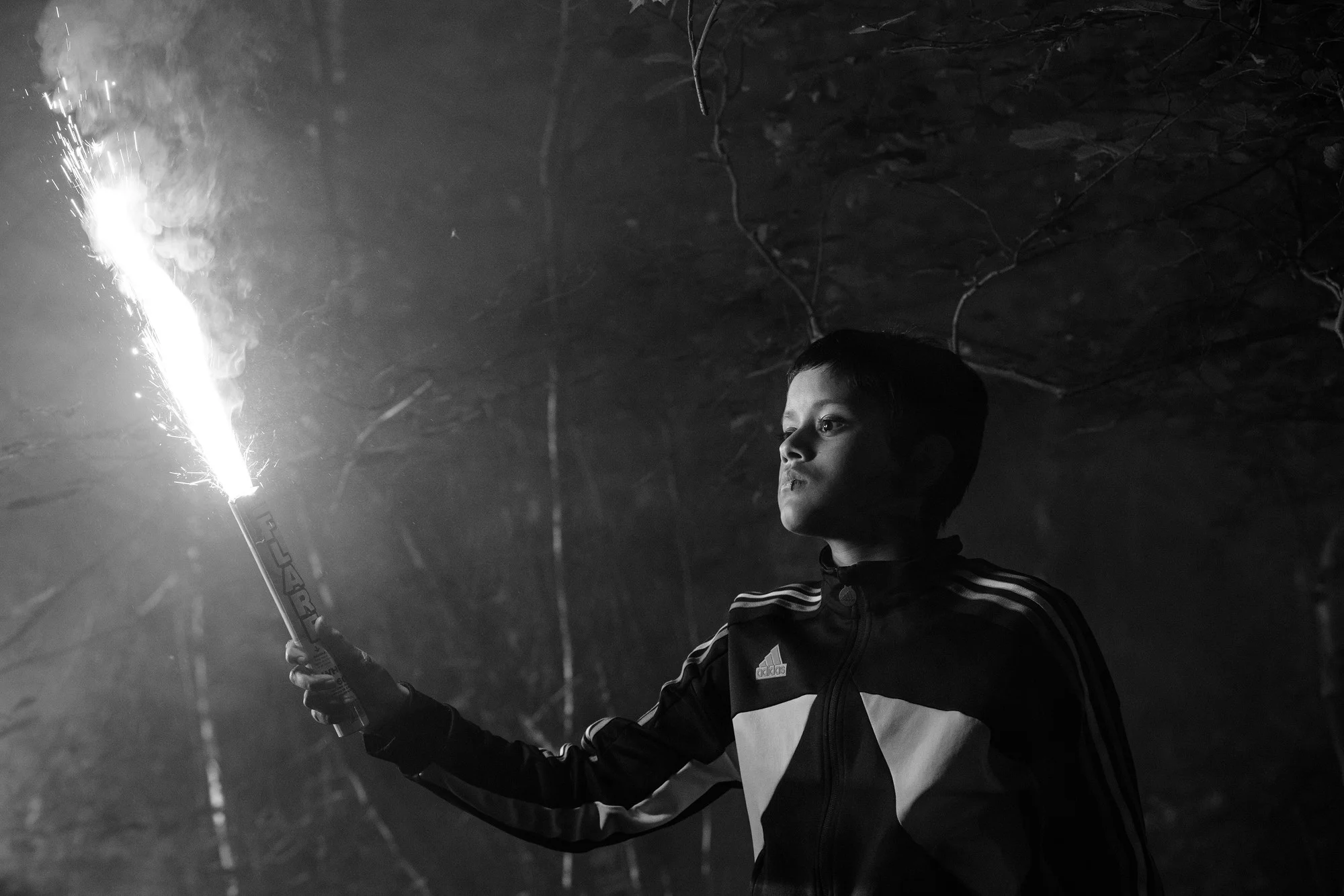 Farhan Hasnat holds a lit flare at night in Ish Perretta film still