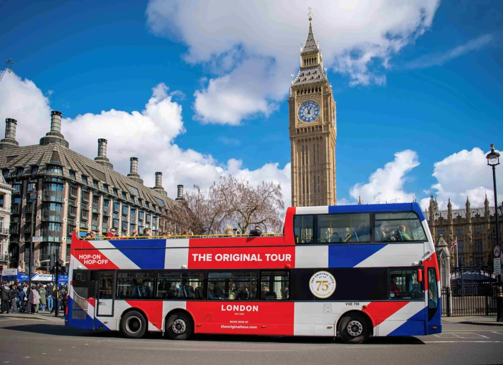 The Original Tour hop on hop off double decker bus in Union Jack livery passing Big Ben and the Houses of Parliament in London