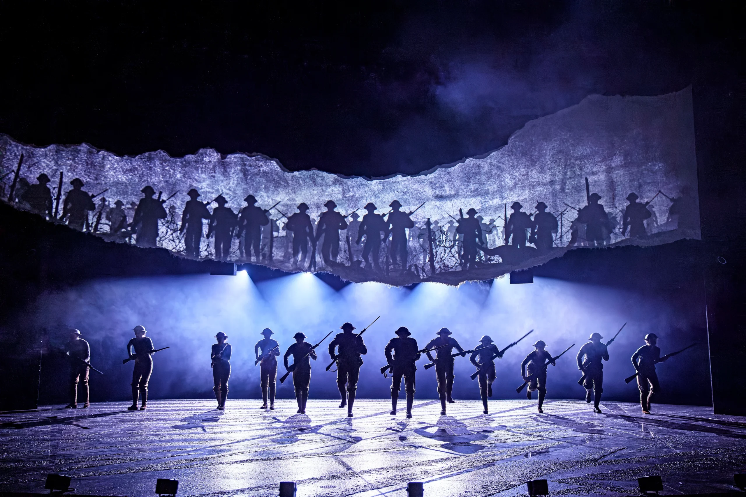 War Horse review, National Theatre soldiers charge in silhouette beneath torn battlefield backdrop