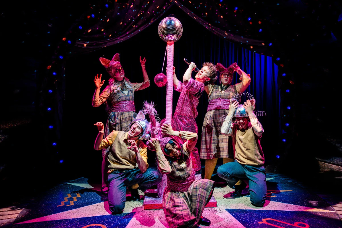 Cast of Ride the Cyclone Southwark strike a dramatic pose around a pink disco ball