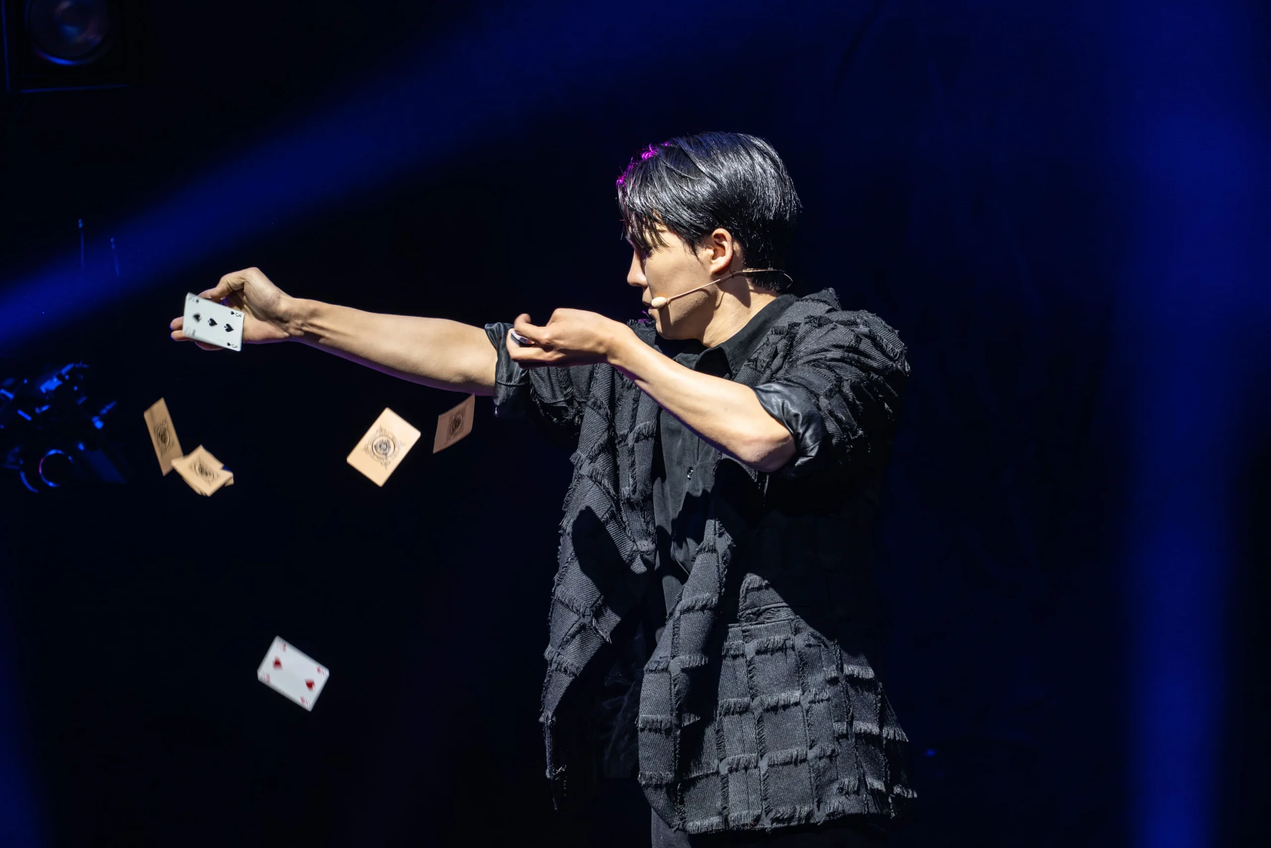 Now You See Me Live magician, Eden Choi, throws cards mid-performance at the London Coliseum