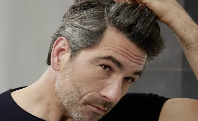Man examining grey hair science mix of grey and dark strands at his hairline